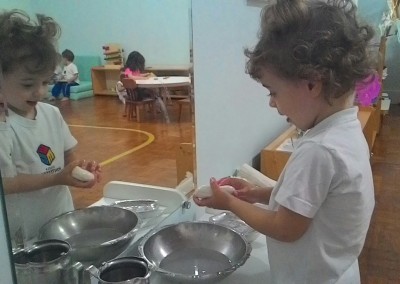 Mariana muito concentrada na atividade de lavar as mãos.