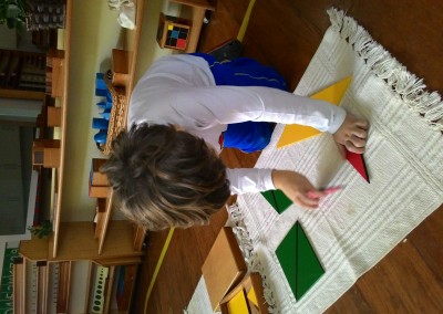 Arthur construindo diferentes formas geométricas com os triângulos da caixa retangular.